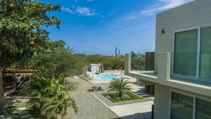 Ein modernes Gebäude mit Pool, umgeben von viel Grün und Palmen.