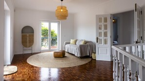 A bedroom with a bed, a round rug, a hanging light fixture, and a view of the outdoors. - Villa Octopus s Garden by Acasadascasas (Mafra)