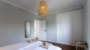 A bedroom with a large bed, a hanging light fixture, a mirror, and a wardrobe. - Villa Octopus s Garden by Acasadascasas (Mafra)