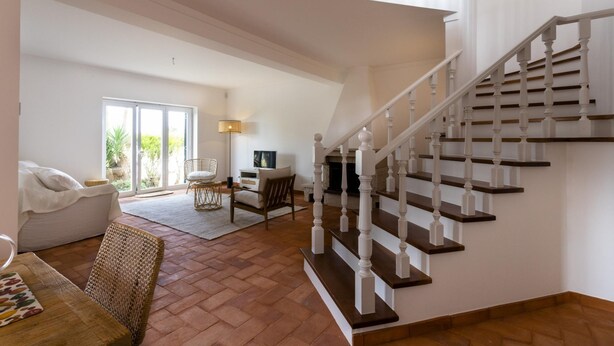 A spacious living area with a staircase, a sofa, a coffee table, and a TV. - Villa Octopus s Garden by Acasadascasas (Mafra)