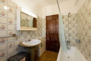 Une salle de bain avec un lavabo, un miroir, une douche et des murs carrelés.