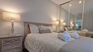 A hotel room with a bed, nightstands, a mirror, and towels. - Ribas Apartment by Acasadascasas (Mafra)
