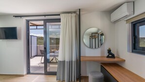 Ein modernes Hotelzimmer mit einer Schiebetür zum Balkon, einem runden Spiegel, einer kleinen Statue und einem Holzboden.