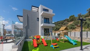 Ein modernes Gebäude mit einem Spielbereich für Kinder, inklusive Rutschen und Schaukeln.