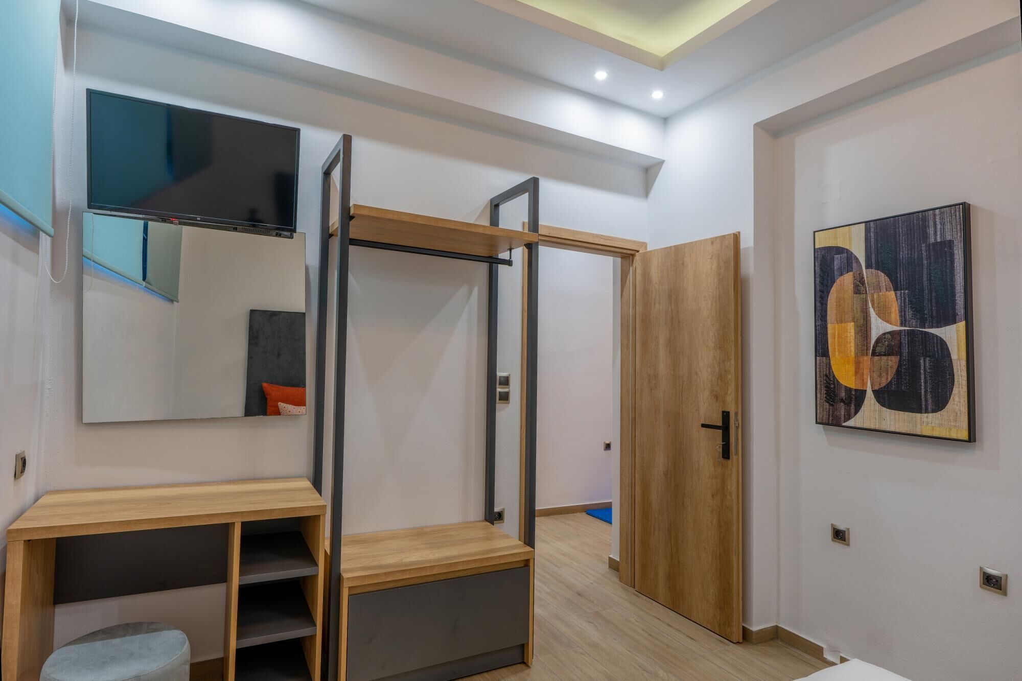 Um interior moderno com uma escrivaninha de madeira, um guarda-roupa com espelho e uma porta que dá para outro quarto.