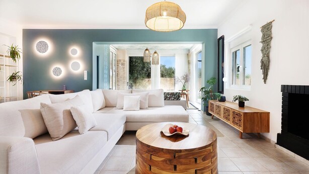 Una sala de estar moderna con un sofá modular, una mesa de centro redonda de madera y vistas al exterior.