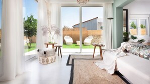 Un dormitorio amplio con una cama grande, vista al jardín a través de puertas corredizas de vidrio y un techo con lámpara de fibra.