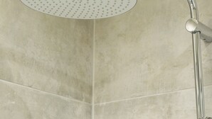Une douche moderne dotée d’un pommeau de douche incurvé et d’un flexible de douche.