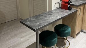 Une cuisine moderne avec un pare-feu en marbre, un plan de travail noir et deux tabourets de bar turquoise.