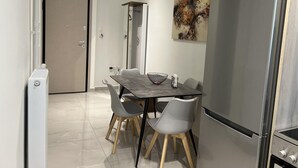 A modern kitchen with a stainless steel refrigerator, a dining table with four chairs, and a painting on the wall. - Adelais in Piraeus With 1 Bedrooms and 1 Bathrooms (Piraeus)
