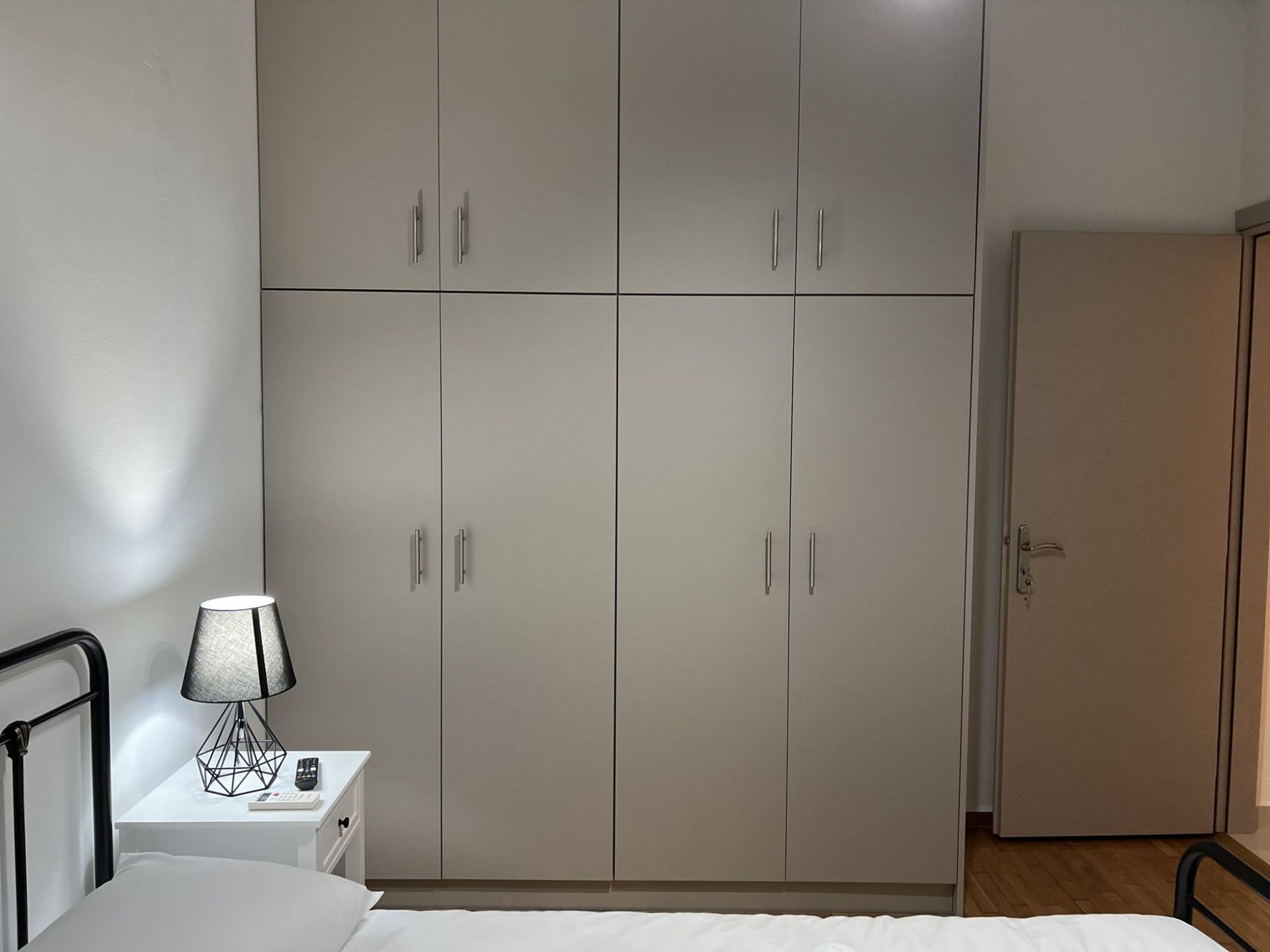 Une chambre à coucher comprenant un lit, une table de chevet, une lampe et une armoire.
