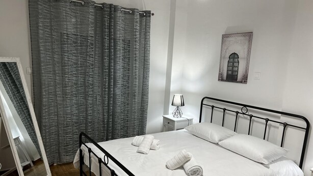 A neatly made bed with white linens and towels, a bedside lamp, and a framed picture on the wall. - Adelais in Piraeus With 1 Bedrooms and 1 Bathrooms (Piraeus)