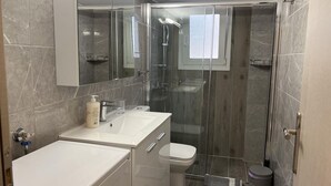 A modern bathroom with a glass-enclosed shower, a toilet, and a sink with a mirror above. - Adelais in Piraeus With 1 Bedrooms and 1 Bathrooms (Piraeus)