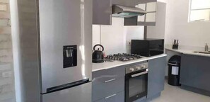 Une cuisine moderne équipée d’appareils électroménagers en acier inoxydable, d’une cuisinière à gaz et d’un four encastré.