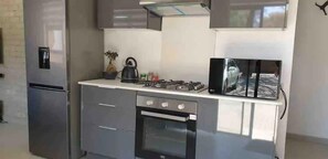 Eine moderne Küche mit einem Edelstahlkühlschrank, einem Backofen, einem Gasherd und einer Mikrowelle.