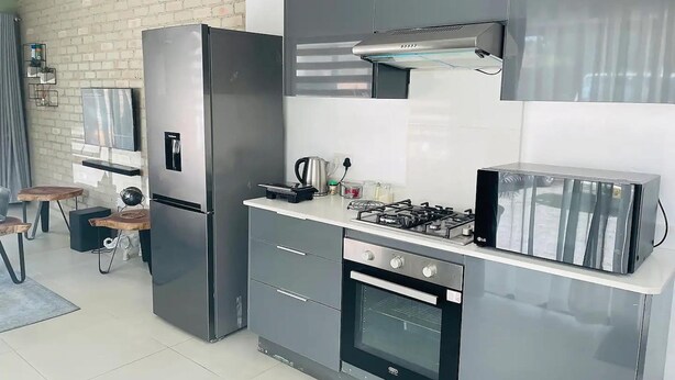 A modern kitchen with a stainless steel refrigerator, a gas stove, and an oven.