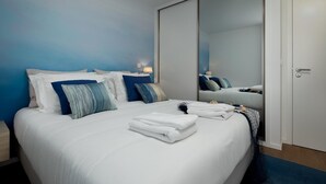 Moderni hotellihuone, jossa on suuri sänky, vaatekaappi ja peili.