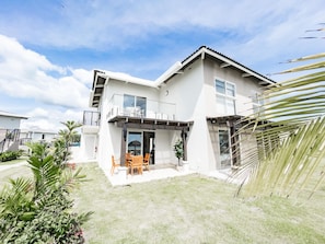 A two-story house with a balcony, a patio with outdoor furniture, and a small garden area. - Residences C6-pba in Chame (Punta Chame)