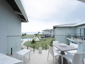 A balcony with a pool view, white furniture, and a clear sky. - Residences C13-1c in Chame (Punta Chame)