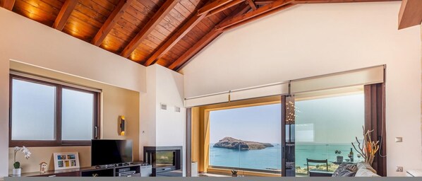 Relax in this spacious living room with a high ceiling, featuring a fireplace and a flat-screen TV.