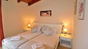 A double bed with striped bedding, two bedside tables with lamps, a wooden ceiling, and a framed picture on the wall. - Katrina Superior Apartment 5 With Balcony (Rethymno)