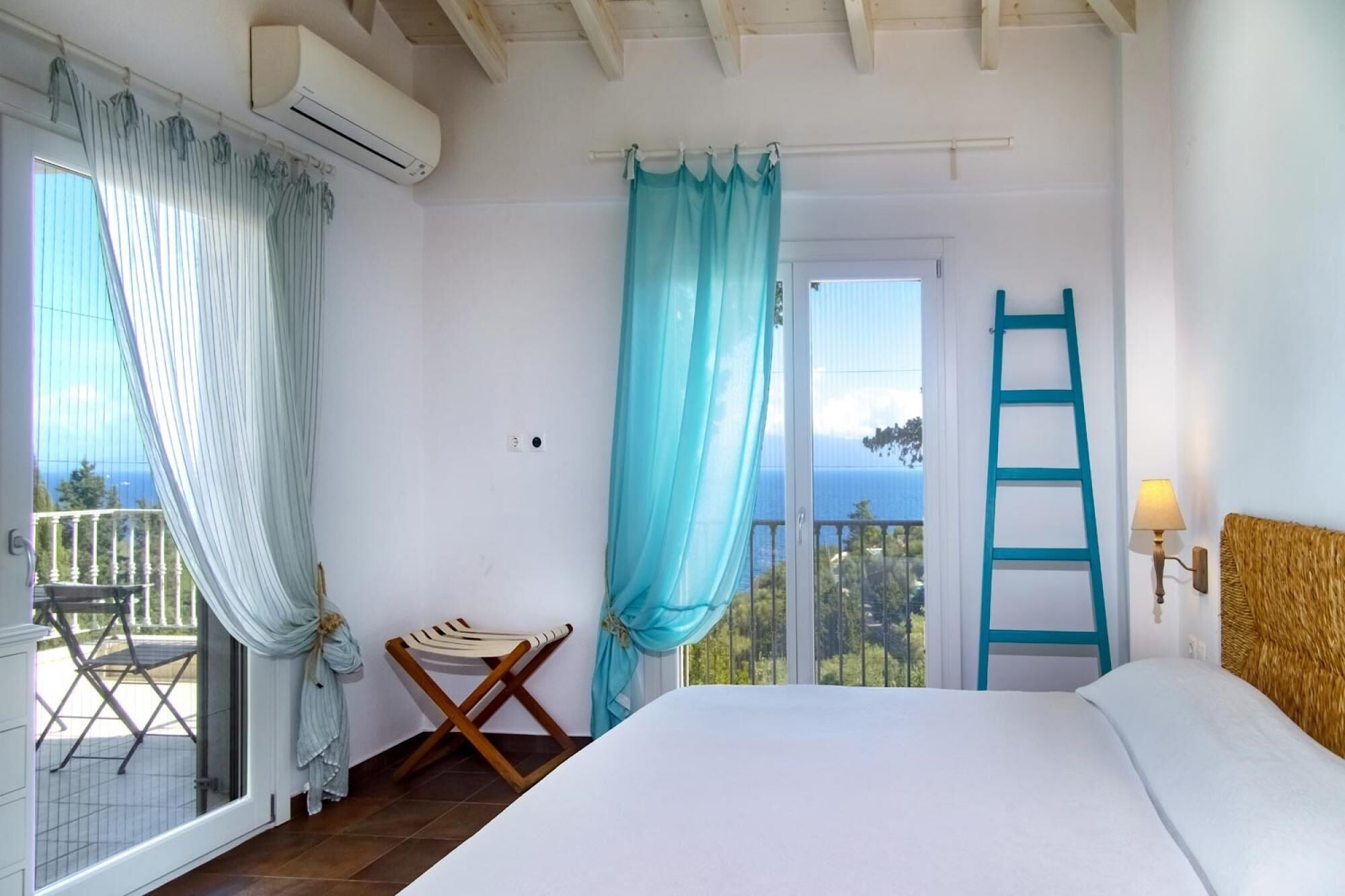 Ein Schlafzimmer mit Bett, einem Balkon mit Stuhl, einer Strickleiter und Meerblick.