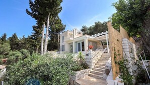 A modern two-story house with a stone staircase leading to a wooden pergola. - Apeiron I Villa - Instaworthy Views Ace Location (Paxos)