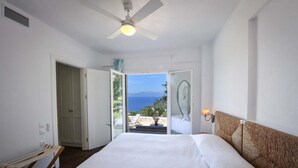 A bedroom with a bed, a ceiling fan, a view of the sea, and a door leading outside. - Apeiron I Villa - Instaworthy Views Ace Location (Paxos)