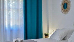 A hotel room with a bed, two rolled towels, a potted plant, and a decorative mirror on the wall. - Apartments for 4 1st Floor (Malevizi)
