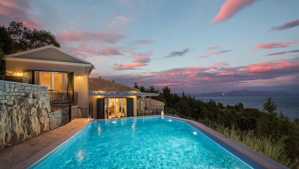 A swimming pool with a stone wall and a view of the sea at sunset. - Danai Villa - Charming Escape With Oceanside Views (Paxos)