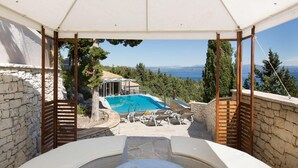 A poolside area with a pergola, outdoor seating, and a view of the sea. - Danai Villa - Charming Escape With Oceanside Views (Paxos)