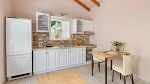 A modern kitchen with white cabinets, a wooden countertop, and a dining area with a table and chairs. - Angelina Villa - Four Bedroom Traditional Paxos Villa (Paxos)