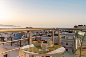 Ein Balkon mit Tisch für zwei Personen, einer Schüssel mit Frühstücksflocken und zwei Tassen.