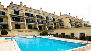 A swimming pool with lounge chairs and a building with balconies. - Kiko s House by Acasadascasas (Mafra)