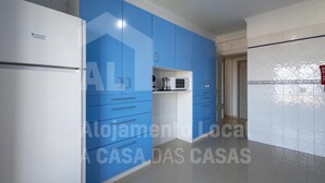 A modern kitchen with blue cabinets, a white refrigerator, and a microwave. - Ocean Apartment by Acasadascasas (Mafra)