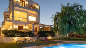 Ein modernes Mehrfamilienhaus mit Swimmingpool, Sitzgelegenheiten im Freien und einem großen Baum.