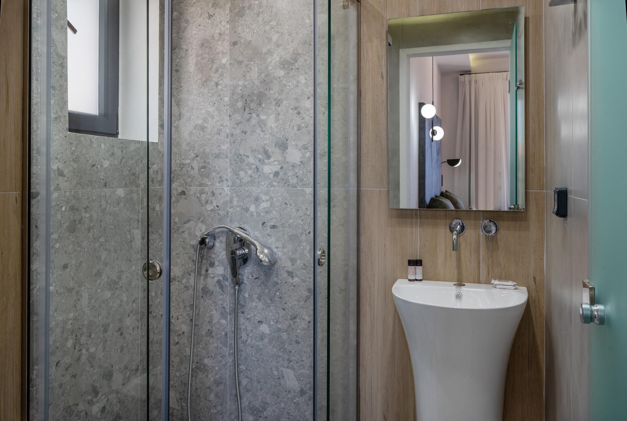 Ein modernes Badezimmer mit einer Duschkabine aus Glas, einem freistehenden Waschbecken und einem Spiegel darüber.