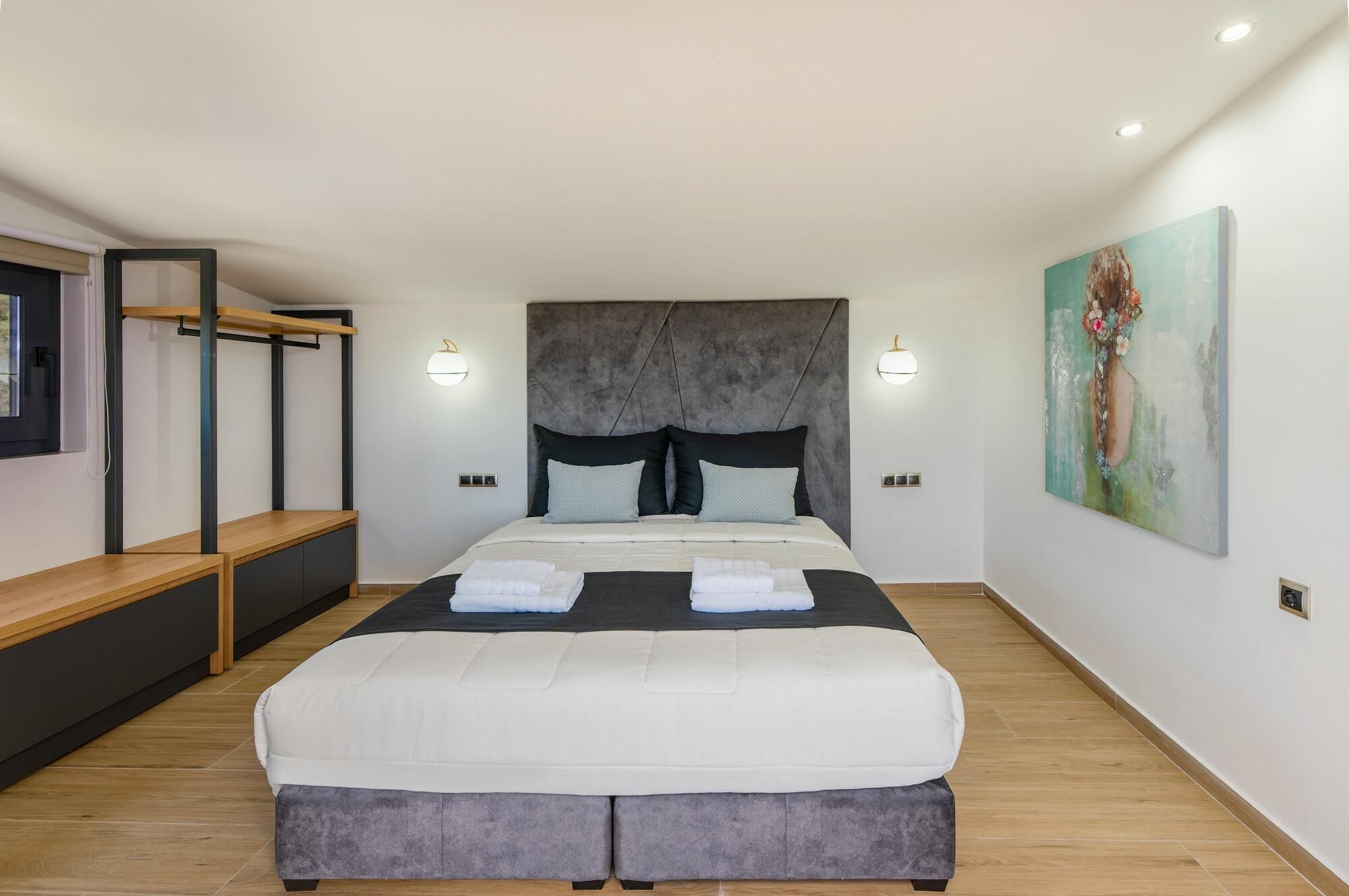 Un dormitorio moderno con una cama grande, mesitas de noche, un banco y un cuadro en la pared.