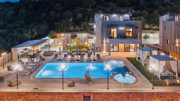En modern villa med pool, utomhusmöbler och utsikt över de omgivande kullarna.
