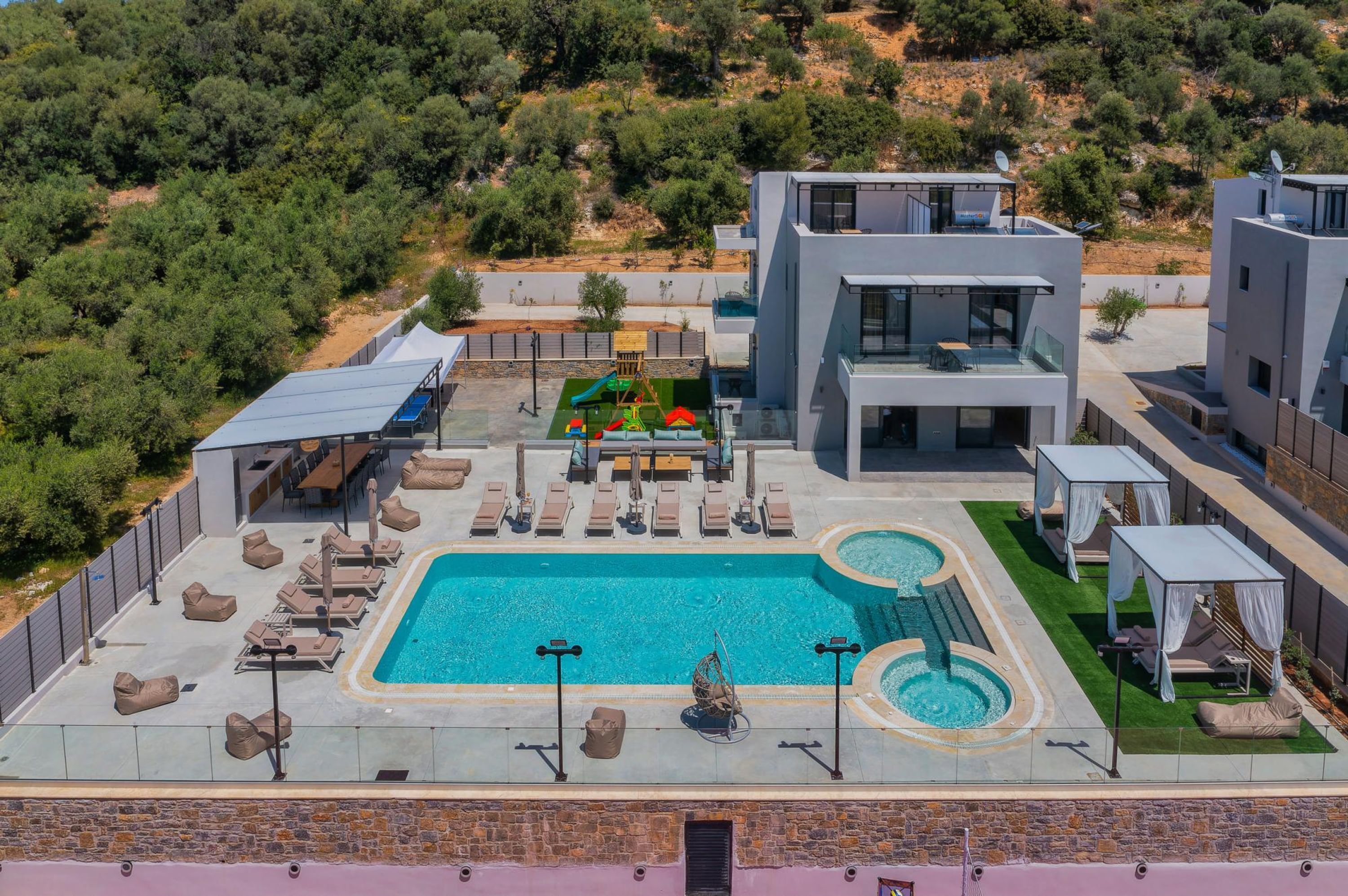 A rooftop pool area with lounge chairs, a hot tub, and a children's play area.