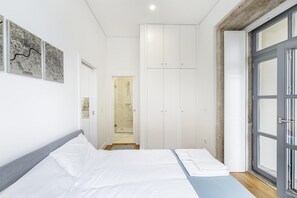 Quarto moderno com cama, guarda-roupa e área de chuveiro.
