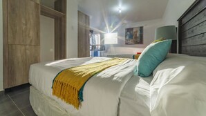 Ein Schlafzimmer mit Bett, Kleiderschrank, Lampe und einem Gemälde an der Wand.