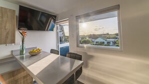Eine moderne Küche mit Essbereich, ein großes Fenster mit Blick auf Häuser und ein Flachbildfernseher über der Arbeitsplatte.