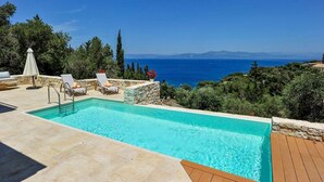 A pool with a view of the sea, surrounded by stone walls and greenery. - Apeiron II Villa - Sunny Modern Pool - Walk to Gaios (Paxos)