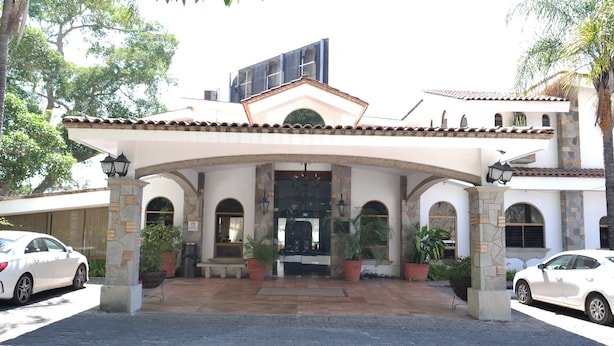 A building with a tiled roof, arched doorways, and potted plants. - Hotel Hacienda las Higueras  (Tepic)