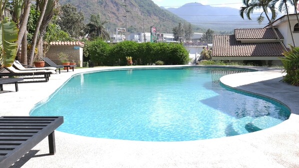 A swimming pool with lounge chairs and a view of a mountainous landscape. - Hotel Hacienda las Higueras (Tepic)