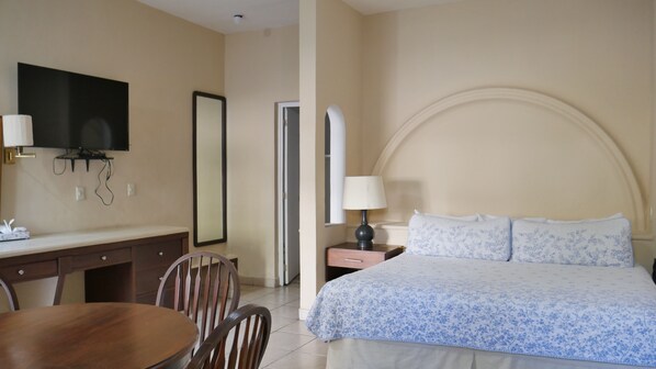 A hotel room with a bed, a desk with a chair, a television, and a mirror. - Hotel Hacienda las Higueras (Tepic)