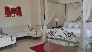 A bedroom with a four-poster bed, a white sofa, and a glass coffee table. - Hotel Hacienda las Higueras  (Tepic)
