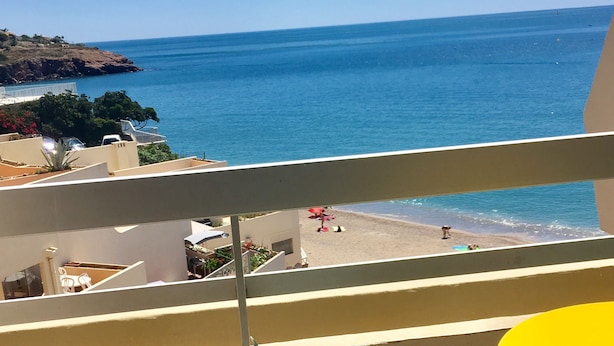 A balcony with a view of the sea, a chair, and a table. - Face mer Plage à 2m Studio 4 Personnes (Sète)