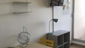 A room with a table, chairs, a TV, and a shelf. - Face mer Plage à 2m Studio 4 Personnes (Sète)
